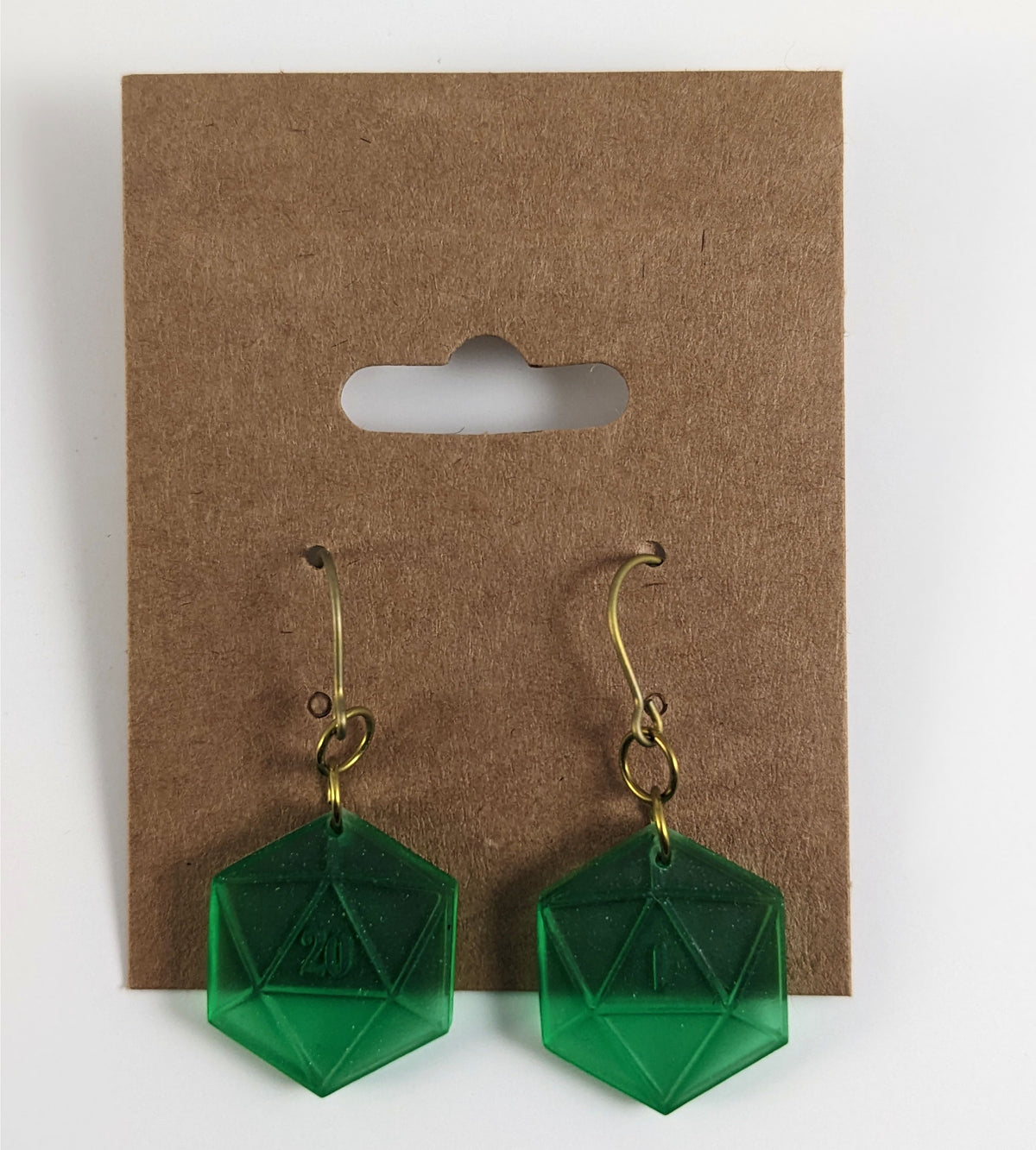 A pair of emerald green dangly, flat d20 earrings with gold color titanium and niobium hardware on a kraft earring card on a white background. The earring on the left has a 20 on it and the earring on the right has a 1 on it, both in a fantasy style font.