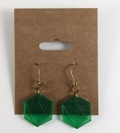 A pair of emerald green dangly, flat d20 earrings with gold color titanium and niobium hardware on a kraft earring card on a white background. The earring on the left has a 20 on it and the earring on the right has a 1 on it, both in a fantasy style font.