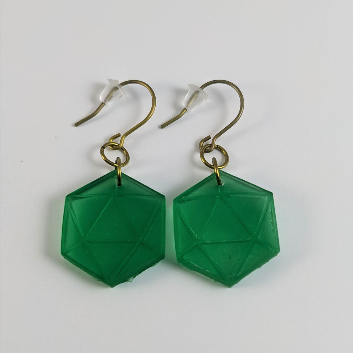 A pair of emerald green dangly, flat d20 earrings with gold color titanium and niobium hardware and bell shaped rubber backs on a white background.