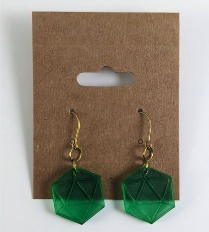 A pair of emerald green dangly, flat d20 earrings with gold color titanium and niobium hardware on a kraft earring card on a white background.