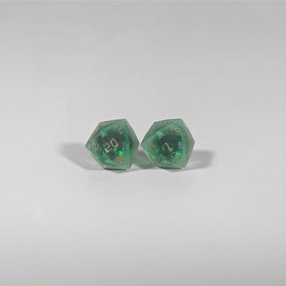 A single pair of the larger size handmade d20 earrings with titanium hardware that are emerald green with gold numbers on a white background. The earring on the left centers the 20 face and the earring on the right centers the 1 face.