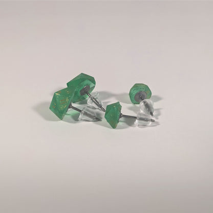 Two pairs of handmade d20 earrings that are emerald green with gold numbers turned to show the titanium hardware and bell shaped rubber backs.