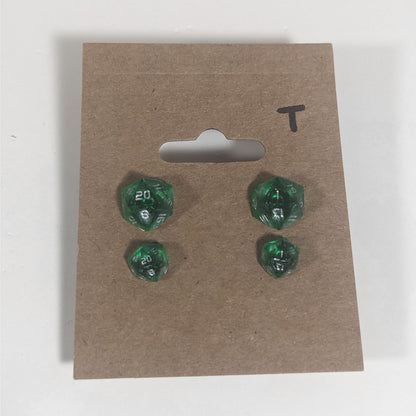 Two pairs of handmade d20 earrings with titanium hardware that are emerald green with silver numbers on a kraft brown earring card with a T in the top right corner. The earrings on the left of each pair centers the 20 face and the earrings on the right of each pair centers the 1 face.