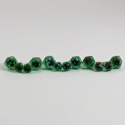 Six pairs of emerald green d20 stud earrings with titanium hardware on a white background. There are 3 large pairs and 3 small pairs, and one pair of each of those has gold numbers, silver numbers, and copper numbers.
