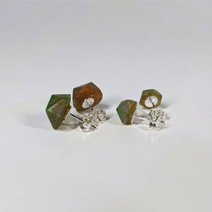 Two pairs of handmade d20 earrings that are bright green and red gold with purple numbers turned to show the sterling silver hardware and butterfly backs.