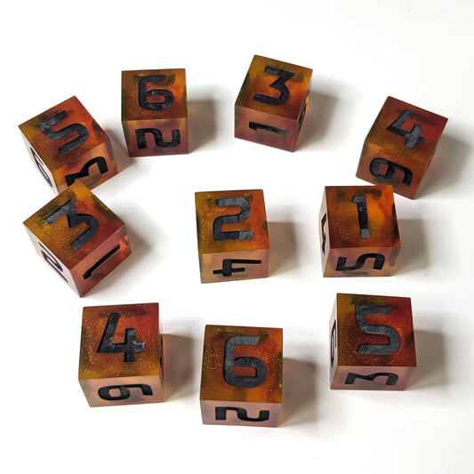 10 red and orange handmade dice with black and gray numbers are scattered on a white background. They have a variety of numbers face up.