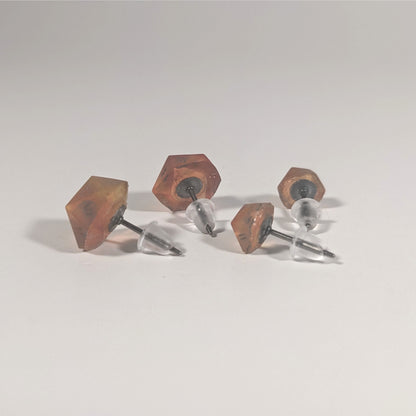 Two pairs of handmade d20 earrings that are red and orange swirls with smokey gray numbers turned to show the titanium hardware and bell shaped rubber backs.
