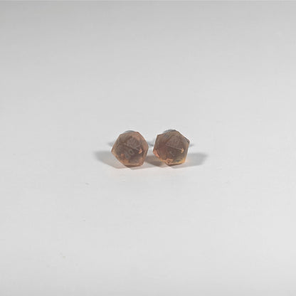 A single pair of the smaller size handmade d20 earrings with titanium hardware that are red and orange swirls with smokey gray numbers on a white background. The earring on the left centers the 20 face and the earring on the right centers the 1 face.