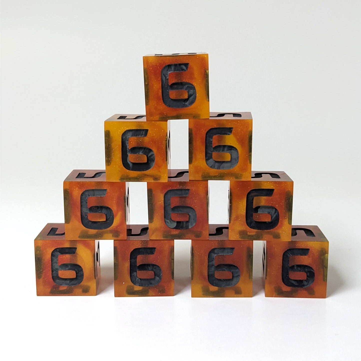 Ten orange and red d6s are stacked into a vertical pyramid on a white background. All the 6 faces are facing forward, and the swirls of black and gray in the numbers are clear.