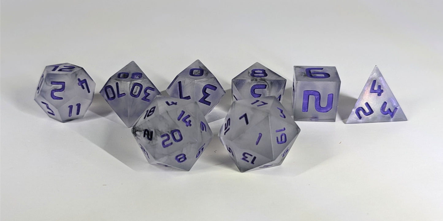 A straight on photo of a standard set of DnD dice that have black swirls around a cloudy insert and purple numbers focusing on 2 d20s in the center. The d20 on the left has the 20 face centered and the d20 on the right has the 1 face centered. The other 6 dice are lined up in the background.