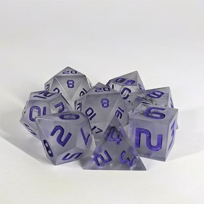 A complete set of 8 handmade artisan dice that have black swirls around a cloudy insert with purple numbers. The DnD dice set is arranged in a circle and features 2 D20s, one of which is in the center surrounded by the other 7 dice.