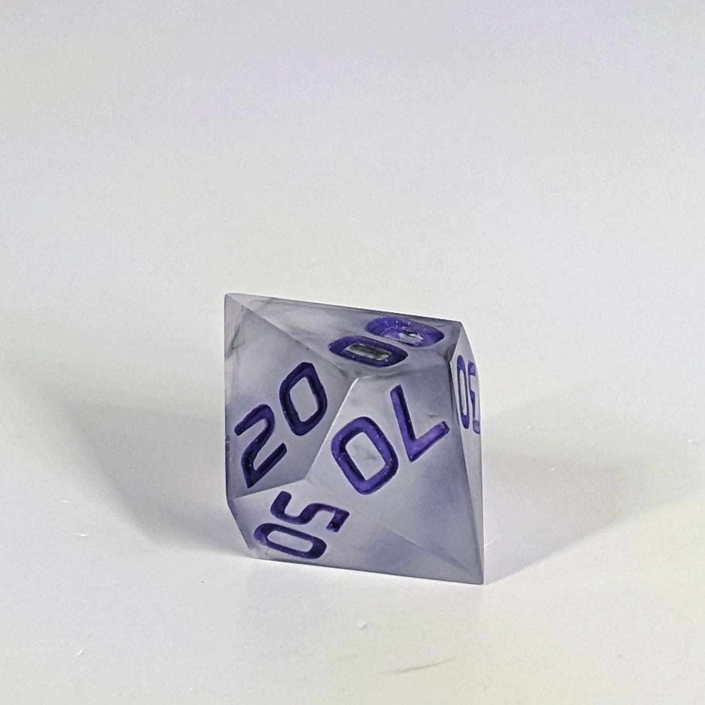 A close up of the d% die showing that a bubble was in the middle of the second 0 on the 00 face. It is a cosmetic flaw that does not affect rolling or the clarity of the number.