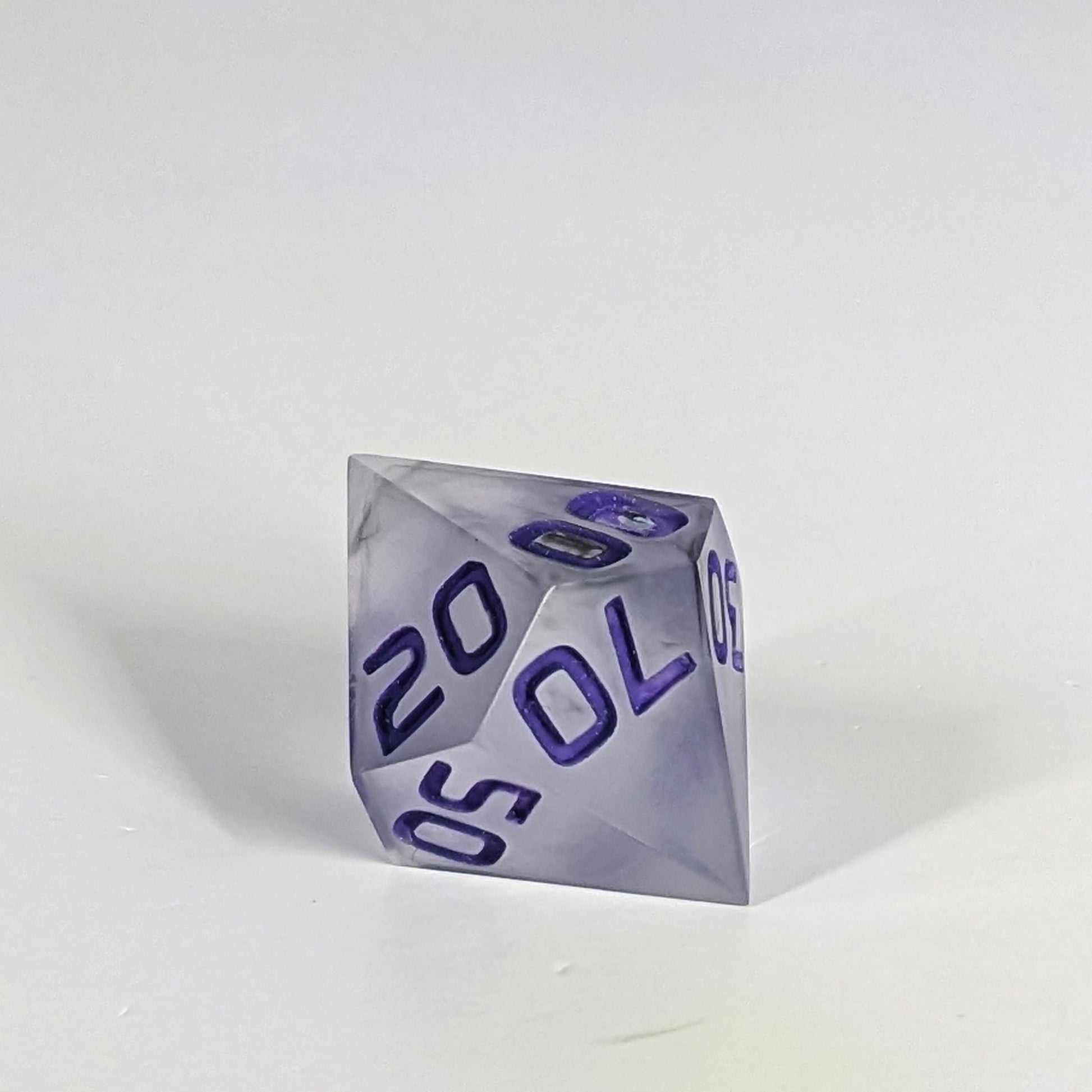 A close up of the d% die showing that a bubble was in the middle of the second 0 on the 00 face. It is a cosmetic flaw that does not affect rolling or the clarity of the number.