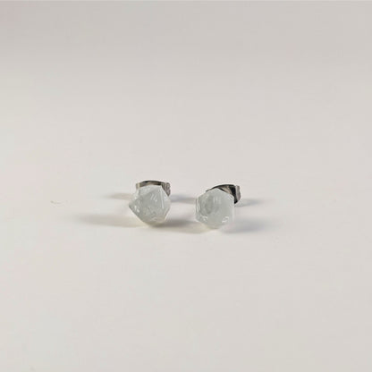 A single pair of the smaller size handmade d20 earrings that are frosty white with white numbers on a white background. The earring on the left centers the 20 face and the earring on the right centers the 1 face.