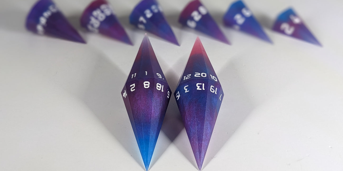 A straight on photo of a dagger set of DnD dice that are purple, pink, and blue galaxy swirls with an extra touch of glitter and white numbers focusing on 2 d20s in the center. The d20 on the left has the 1 face up and the d20 on the right has the 20 face up. The other 6 dice are lined up in the background but are out of focus, while the d20s are in sharp focus.