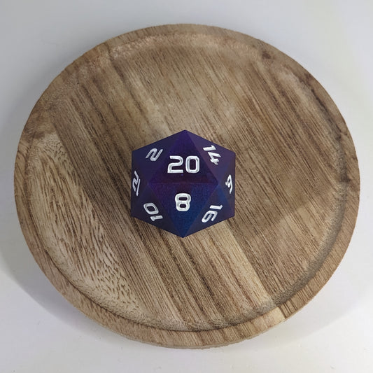 A high angle view of a large d20 with subtle swirls of purple, blue, and pink with white numbers. It is sitting in the center of a wooden circle.