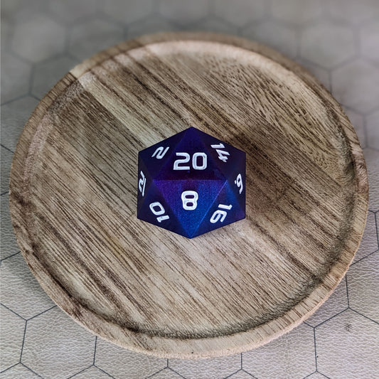 A high angle view of a large d20 with subtle swirls of purple, blue, and pink with white numbers. It is sitting in the center of a wooden circle.