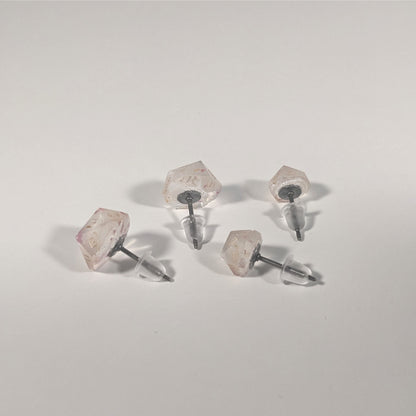 Two pairs of handmade d20 earrings that are glittery clear with pink flakies with gold numbers turned to show the titanium hardware and bell shaped rubber backs.