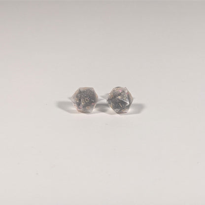 A single pair of the smaller size handmade d20 earrings with titanium hardware that are glittery clear with pink flakies with gold numbers on a white background. The earring on the left centers the 20 face and the earring on the right centers the 1 face.