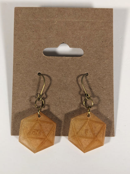 A pair of sparkly gold dangly, flat d20 earrings with gold color titanium and niobium hardware on a kraft earring card on a white background. The earring on the left has a 20 on it and the earring on the right has a 1 on it, both in a sci-fi style font.
