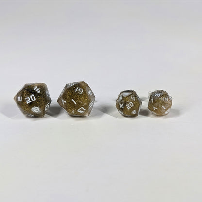 Two pairs of handmade d20 earrings with sterling silver hardware that are glittering gold and black with white numbers on a white background sit in a line with the larger pair on the left and the smaller pair on the right. The earrings on the left of each pair centers the 20 face and the earrings on the right of each pair centers the 1 face.