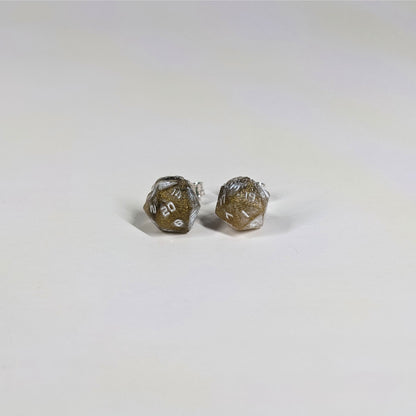 A single pair of the smaller size handmade d20 earrings with sterling silver hardware that are glittering gold and black with white numbers on a white background. The earring on the left centers the 20 face and the earring on the right centers the 1 face.
