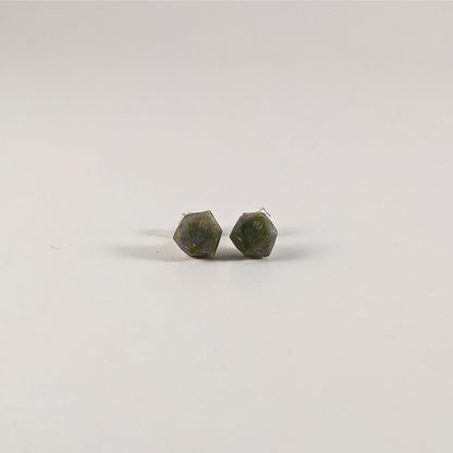 A single pair of the smaller size handmade d20 earrings with sterling silver hardware that are dark green and bright gold with purple numbers on a white background. The earring on the left centers the 20 face and the earring on the right centers the 1 face.