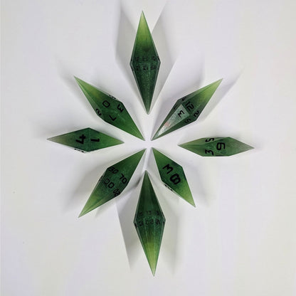 A complete set of diamond shaped resin dice featuring 2 d20s. These handmade dice are swirling shades of green with black numbers and are clustered in a circle with the bottom points angled toward a central point on a white background.