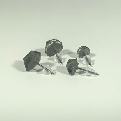 Two pairs of handmade d20 earrings that are swirls of green with black numbers turned to show the titanium hardware and bell shaped rubber backs.