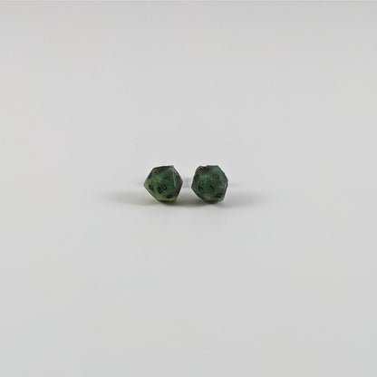 A single pair of the smaller size handmade d20 earrings with titanium hardware that are swirls of green with black numbers on a white background. The earring on the left centers the 20 face and the earring on the right centers the 1 face.