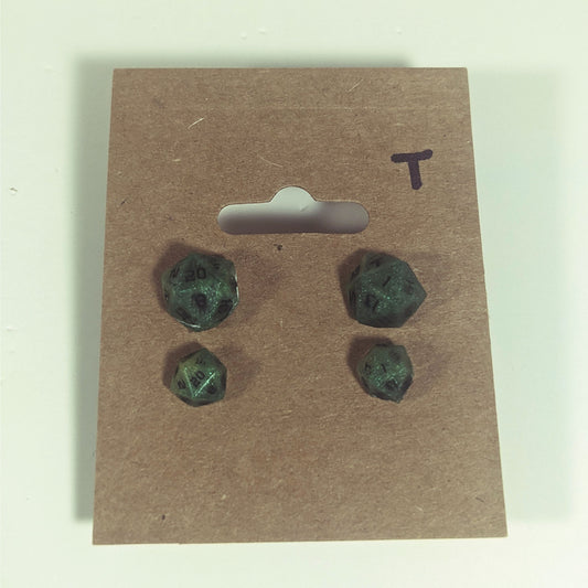 Two pairs of handmade d20 earrings with titanium hardware that are swirls of green with black numbers on a kraft brown earring card with a T in the top right corner. The earrings on the left of each pair centers the 20 face and the earrings on the right of each pair centers the 1 face.