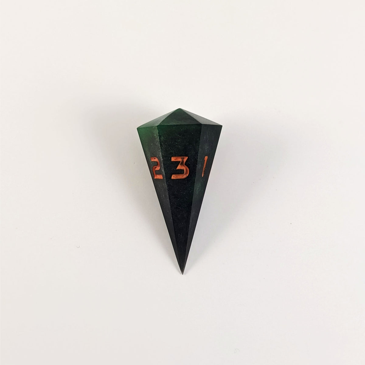 A high angle view of a dagger d3 with swirls of black and green with orange numbers that glow in the dark on a white background.