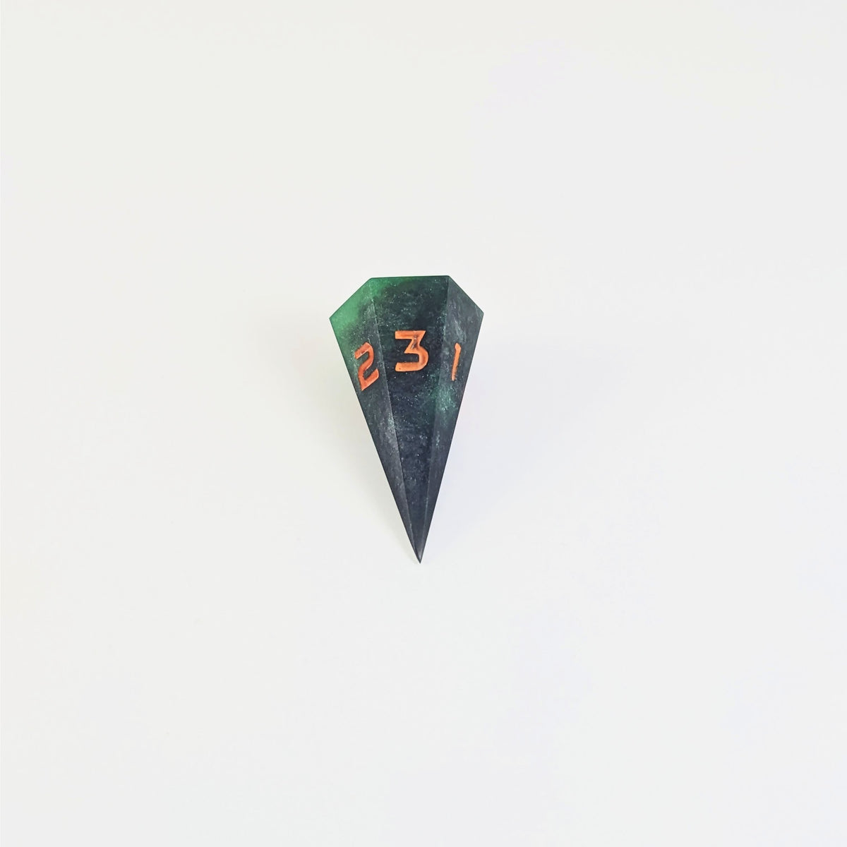 A mid angle view of a dagger d3 with swirls of black and green with orange numbers that glow in the dark on a white background.