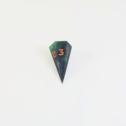 A mid angle view of a dagger d3 with swirls of black and green with orange numbers that glow in the dark on a white background.