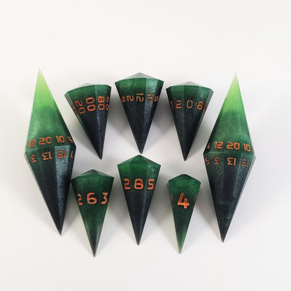 A dagger style DnD dice set that is  green and black with orange numbers that glow in the dark is arranged with a d20 each on the right and left, with the d%, d12, and d10 along the top and the d6, d8, and d4 along the bottom, all in line with the d20s.