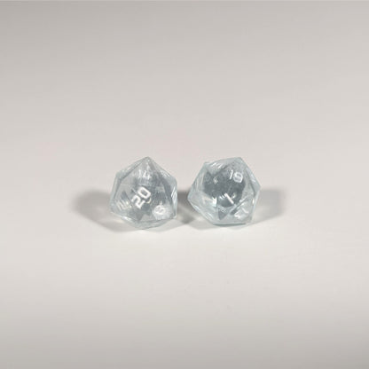 A single pair of the larger size handmade d20 earrings with titanium hardware that are frosty blue and white with white numbers on a white background. The earring on the left centers the 20 face and the earring on the right centers the 1 face.