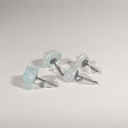 Two pairs of handmade d20 earrings that are frosty blue and white with white numbers turned to show the titanium hardware and bell shaped rubber backs.