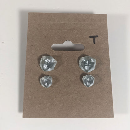 Two pairs of handmade d20 earrings with titanium hardware that are frosty blue and white with white numbers on a kraft brown earring card with a T in the top right corner. The earrings on the left of each pair centers the 20 face and the earrings on the right of each pair centers the 1 face.