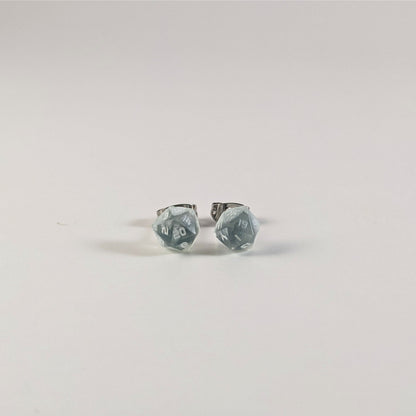 A single pair of the smaller size handmade d20 earrings that are transparent white with hints of glittery blue and opaque white numbers on a white background. The earring on the left centers the 20 face and the earring on the right centers the 1 face.