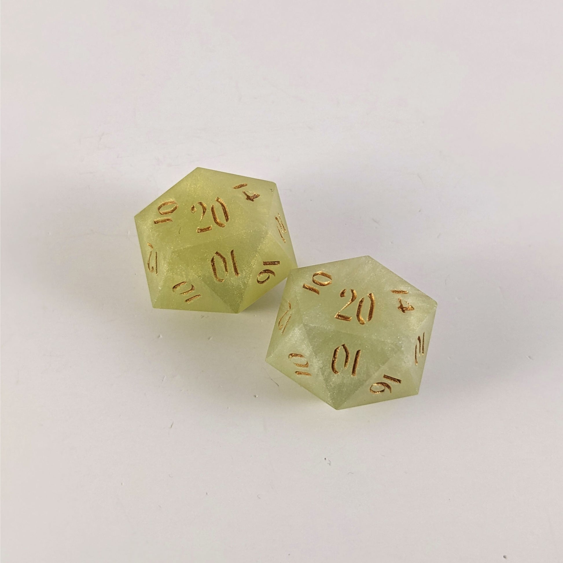 Two handmade reliable talent d20s on a white background. The dice are all light green with gold numbers, showing the variety in shade of green making each die unique. Faces that would be 9 or below are replaced with a 10.