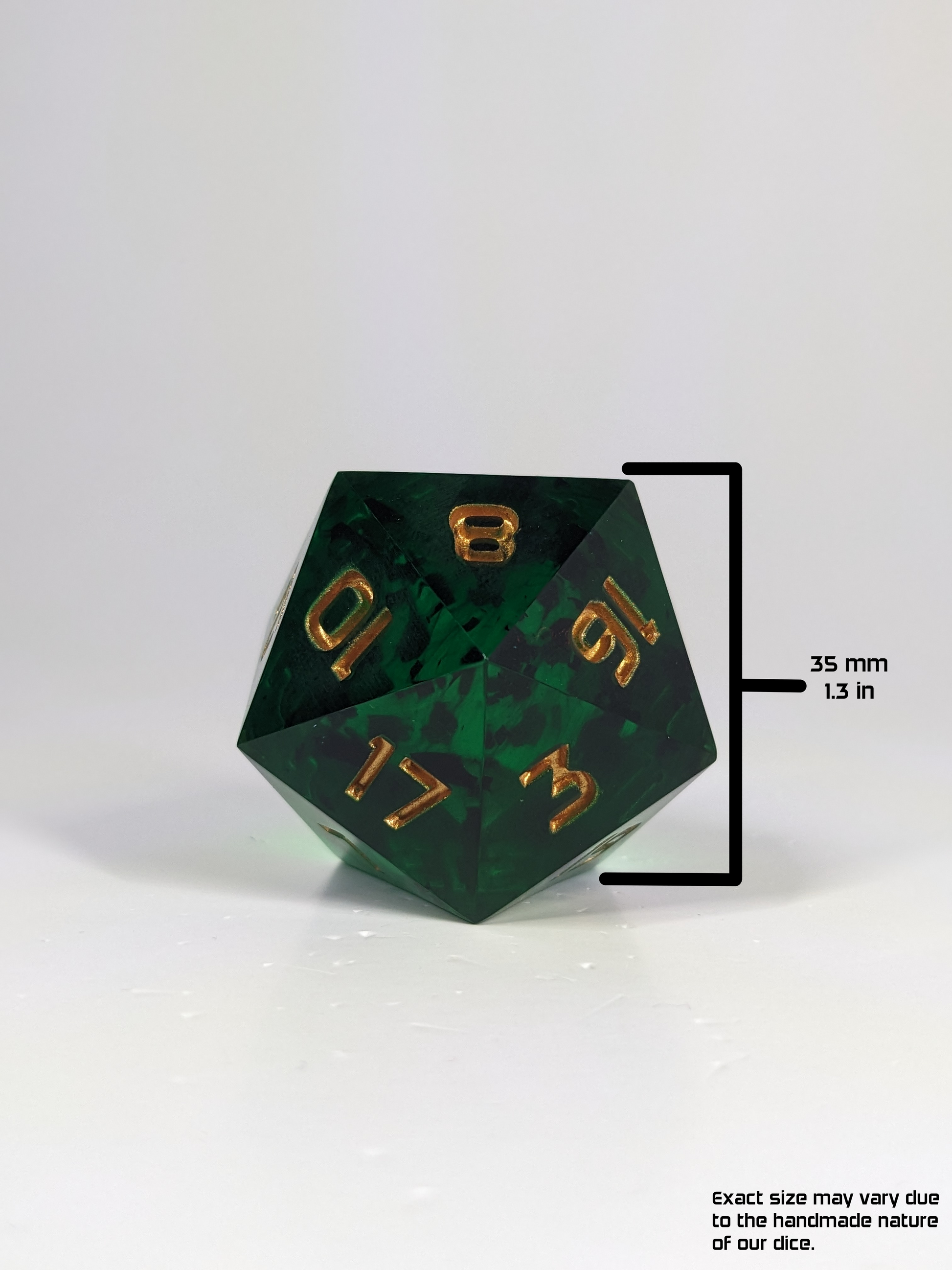  A straight on view of a large d20 that is green with black flakies and gold numbers. A digital overlay measures the height of the die, face to face and notes it as being 35 mm or 1.3 in tall. The bottom right corner has a note that reads “Exact size may vary due to the handmade nature of our dice.”
