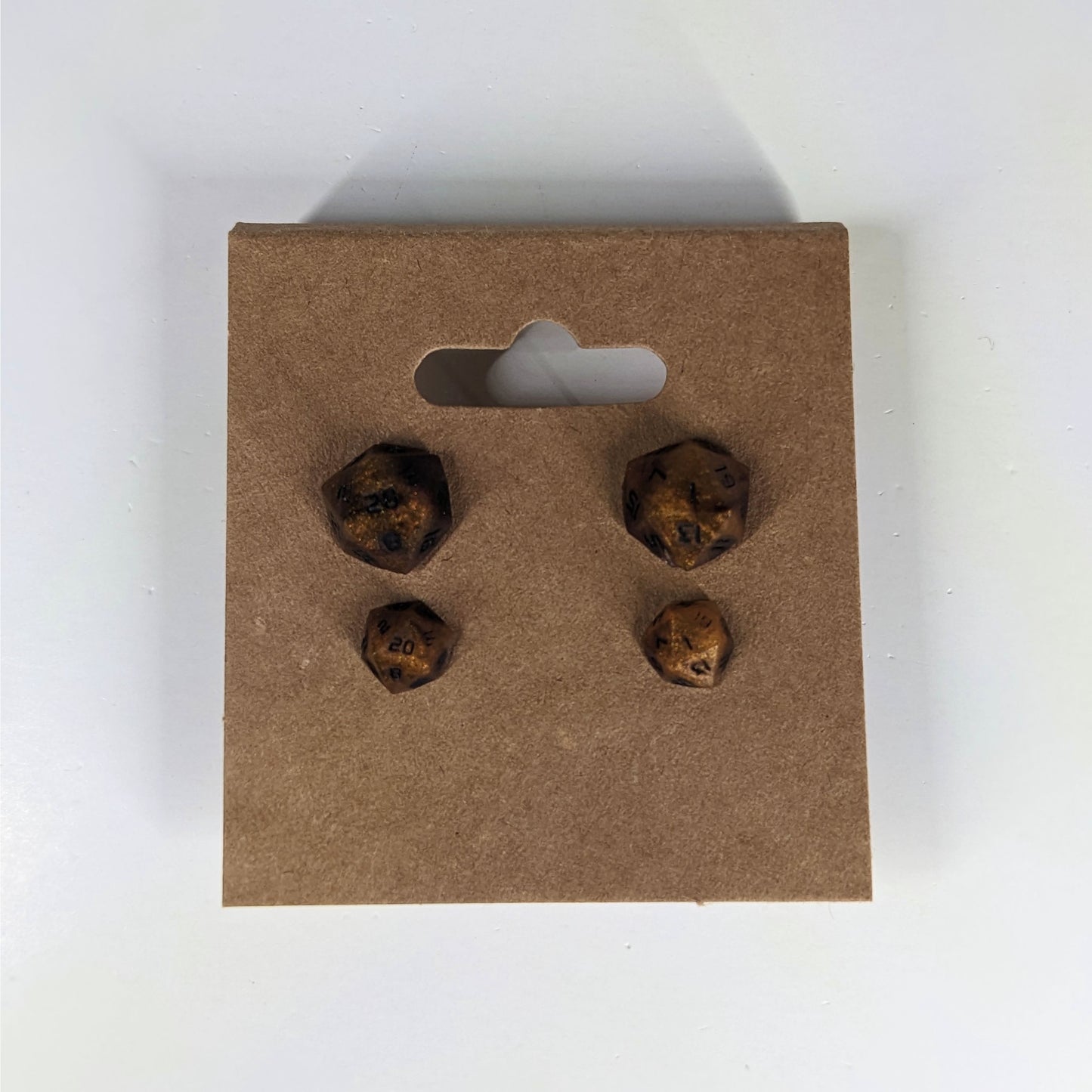 Two pairs of handmade d20 earrings that are orange and deep red with black numbers on a kraft brown earring card. The earrings on the left of each pair centers the 20 face and the earrings on the right of each pair centers the 1 face.