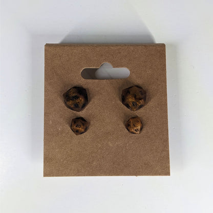 Two pairs of handmade d20 earrings that are orange and deep red with black numbers on a kraft brown earring card. The earrings on the left of each pair centers the 20 face and the earrings on the right of each pair centers the 1 face.
