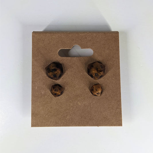 Two pairs of handmade d20 earrings that are orange and deep red with black numbers on a kraft brown earring card. The earrings on the left of each pair centers the 20 face and the earrings on the right of each pair centers the 1 face.