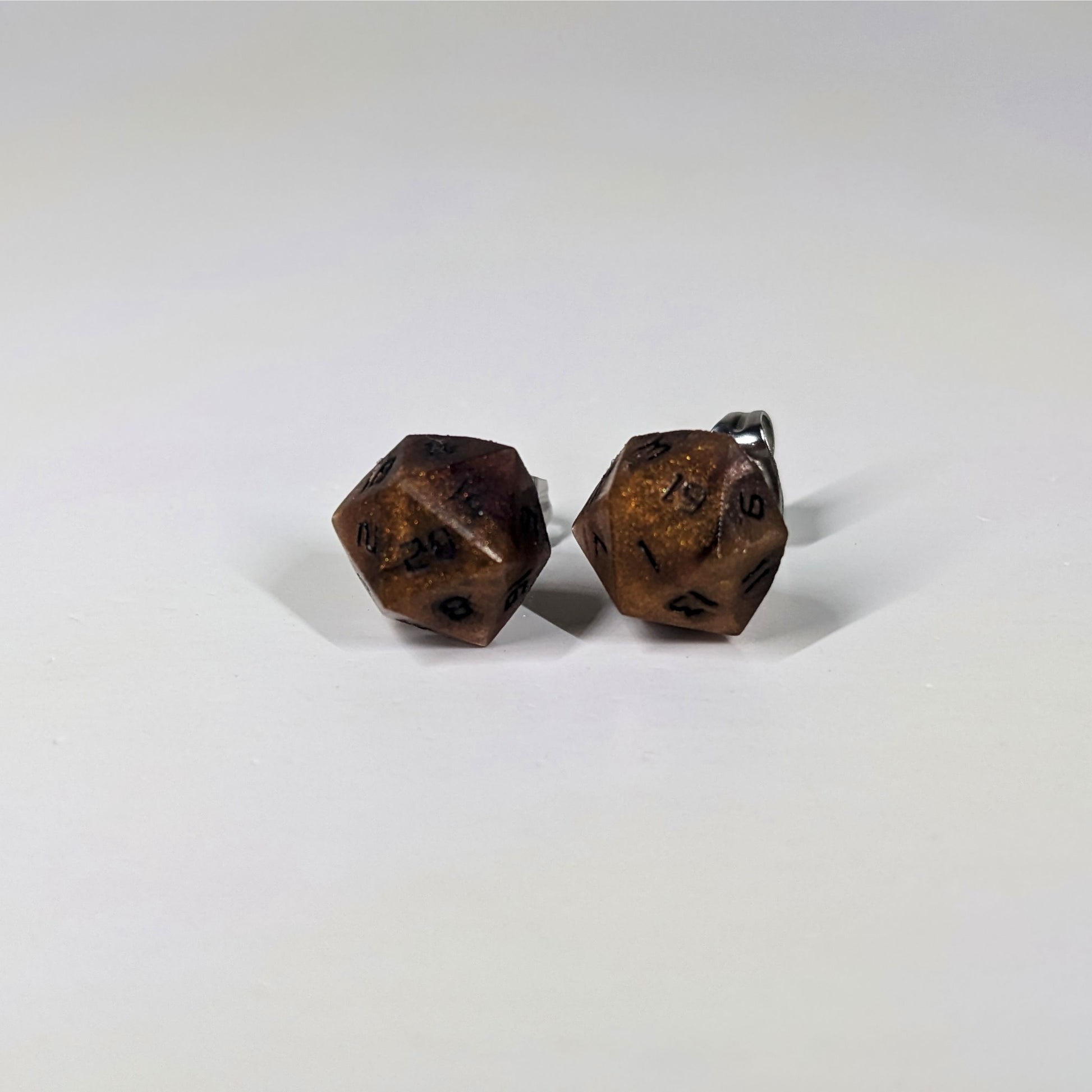 A single pair of the larger size handmade d20 earrings that are orange and deep red with black numbers on a white background. The earring on the left centers the 20 face and the earring on the right centers the 1 face.