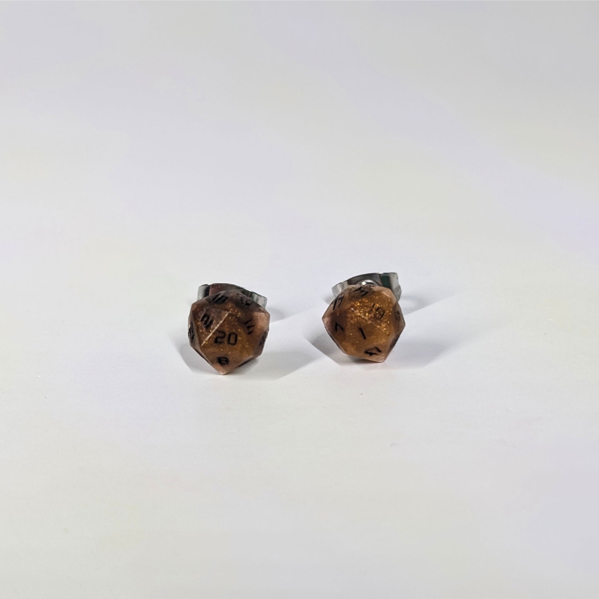 A single pair of the smaller size handmade d20 earrings that are orange and deep red with black numbers on a white background. The earring on the left centers the 20 face and the earring on the right centers the 1 face.
