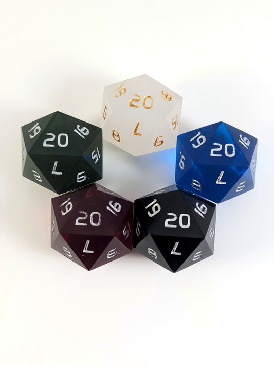 Five spindown d20s with a left spin arranged in a circle with the 20 face on top. White with gold numbers is at the top and blue, black, red, and dark green all with silver numbers follow going clockwise.