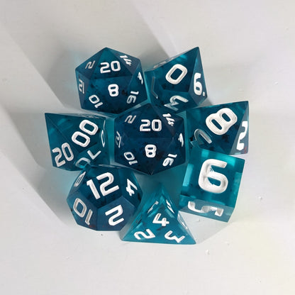 A complete set of 8 handmade artisan dice that are blue with red flakies and white numbers. The DnD dice set is arranged in a circle and features 2 D20s, one of which is in the center surrounded by the other 7 dice. 