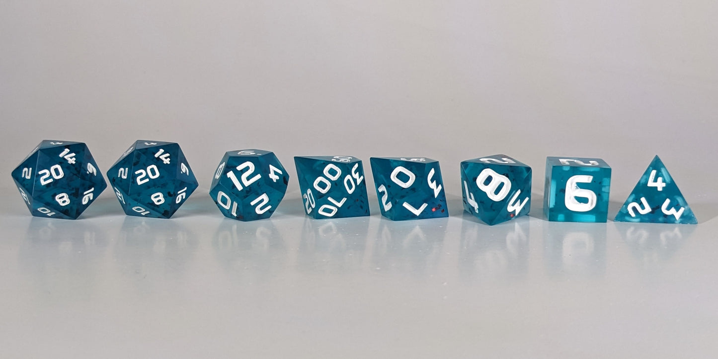 A straight on photo of a complete set of polyhedral dice that are blue with red flakies and white numbers arranged in a straight line. They are lined up with the 2 d20s on the left going down to the d4 on the right side. The highest value number of each die is facing forward.