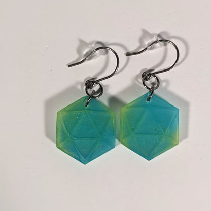 A pair of teal and yellow dangly, flat d20 earrings with silver color titanium and niobium hardware and bell shaped rubber backs on a white background.